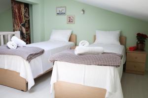 2 bedden in een kamer met witte lakens en handdoeken bij Green Apartment in Leptokaria in Leptokarya