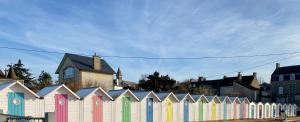 a row of colorful fences in front of a city at A deux pas d'la mer in Grandcamp-Maisy