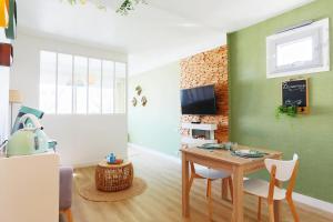 salon ze stołem i zieloną ścianą w obiekcie Appart'Confort - Le Natura w mieście Saint-Brieuc