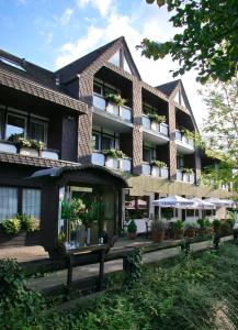 ein Gebäude mit Topfpflanzen und Sonnenschirmen davor in der Unterkunft Landhotel Laarmann in Lennestadt