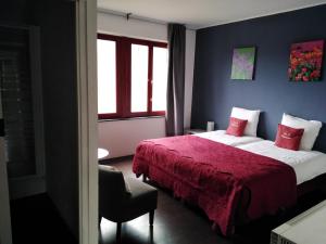 um quarto com 2 camas e um cobertor vermelho em B&B Pittoresque em Houffalize