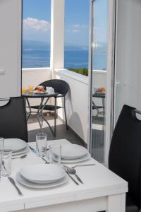 a white table with plates and silverware on a balcony at Sunny Biokovo Apartments in Bast