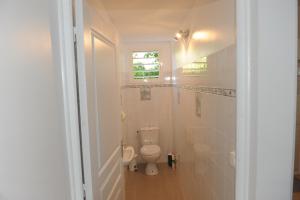 a white bathroom with a toilet in a hallway at Villa Yona in Sainte-Anne