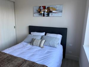 uma cama com lençóis e almofadas azuis num quarto em Hermoso departamento nuevo en costanera de Puerto Varas em Puerto Varas