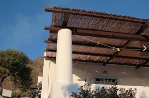 a building with a wooden roof and a pole at Casa Mare Blu in Ginostra