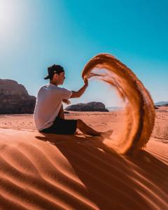 un hombre sentado en la arena en el desierto en Wadi Rum en Wadi Rum