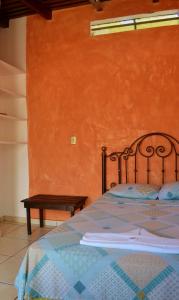 Cama en habitación con pared de color naranja en Hotel Villa Florencia Centro Histórico, en San Salvador