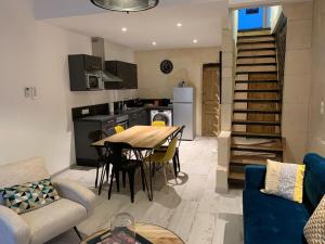 a kitchen and living room with a table and a couch at Le refuge des arènes in Arles