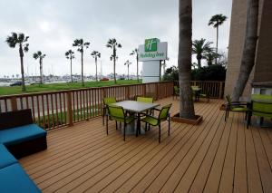 Una terraza de madera con una mesa y sillas. en Holiday Inn Corpus Christi Downtown Marina by IHG, en Corpus Christi