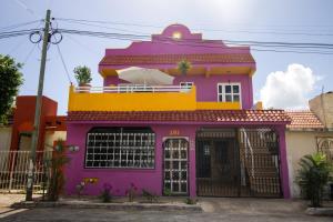 a pink and yellow house with a balcony at Casa Zac Nicte Mx-Habitacion IXCHEL in Cancún