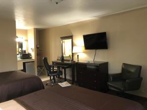 Habitación de hotel con cama, escritorio y TV. en Value Inn Motel EUGENE AIRPORT en Eugene