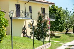 Ein Mann mit einem Kinderwagen vor einem Haus. in der Unterkunft Agriturismo alla Solagna in Colli del Tronto