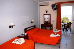 a bedroom with two red beds and a dining room at Captains Hotel in Argassi