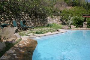 uma piscina com duas cadeiras ao lado de uma parede de pedra em Podere Pian De' Cortini em Serravalle