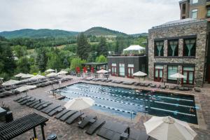 a large pool with chairs and umbrellas next to a building at Westin Riverfront Penthouse in Beaver Creek