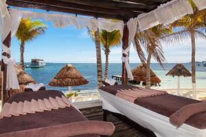 two beds on a beach with palm trees and the ocean at Ocean View Cancun Arenas in Cancún