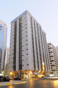 a large white building with cars parked in front of it at Emirates Plaza Hotel in Abu Dhabi