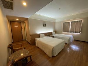 東港的住宿－大鵬灣度假酒店，酒店客房设有两张床和一张桌子。