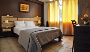 1 dormitorio con cama, escritorio y ventana en Hotel Chimu, en Trujillo