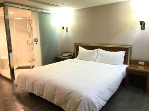 una camera da letto con un grande letto con lenzuola e cuscini bianchi di Tapeng Bay Holiday Hotel a Donggang