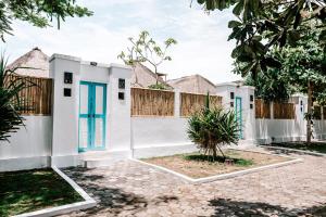 een wit huis met blauwe deuren en een hek bij Bamboo Bungalows in Nusa Lembongan