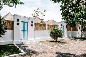 ein weißes Haus mit blauen Türen und einem Zaun in der Unterkunft Bamboo Bungalows in Nusa Lembongan