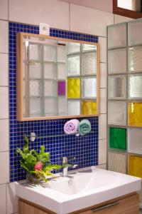 La salle de bains est pourvue d'un lavabo, d'un miroir et de carrelage bleu. dans l'établissement Kovailani 1232 DTO-MT, à Bora Bora