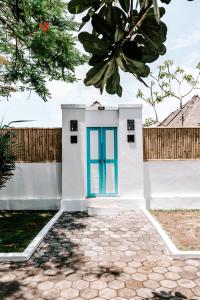 mały biały dom z niebieskimi drzwiami w obiekcie Bamboo Bungalows w mieście Nusa Lembongan