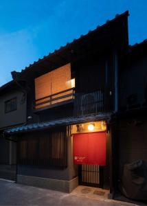 a building with a red door and a balcony at Tsumugi Horikawarokkaku in Kyoto