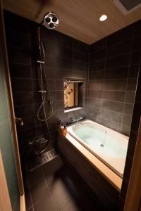a bathroom with a tub and a shower at Tsumugi Horikawarokkaku in Kyoto