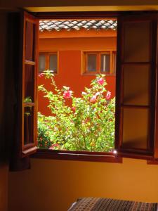 an open window with a bush of flowers behind it at Hotel Pakaritampu in Ollantaytambo