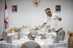 a chef standing in front of a table with white tables at d'primahotel Petitenget Seminyak 2 in Seminyak