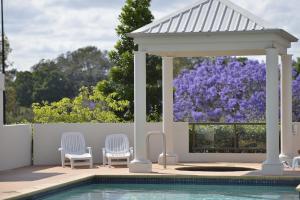 a gazebo and chairs next to a swimming pool at The Oasis Apartments in Brisbane