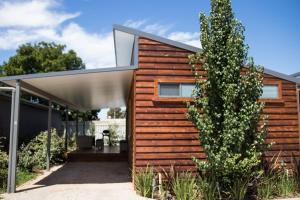 a house with a wooden wall and a tree at Mudgee Apartments on Horatio Street in Mudgee