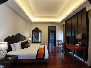 a bedroom with a bed and a desk and a television at Le Palais Juliana in Luang Prabang