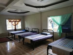 Habitación con 4 camas y ventanas. en Mulu Diana Homestay en Mulu