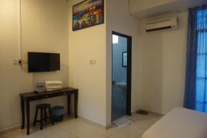 a room with a bed and a desk and a television at S & S Guest House Kuantan in Kuantan