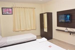 a bedroom with two beds and a flat screen tv at Arihanth Inn in Vellore