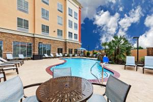 a patio with a table and chairs and a pool at Clarion Hotel The Colony - Plano West in The Colony