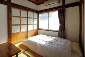 Habitación pequeña con cama y ventana en Fujiyoshida Youth Hostel en Fujiyoshida