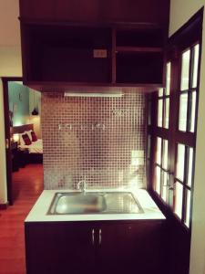 a kitchen with a sink and a tiled wall at Mandala House, Chiang Mai in Chiang Mai