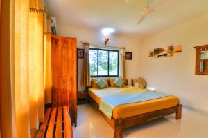 a bedroom with a bed and a window at Monarch Suites in Candolim