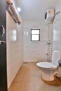 Un baño blanco con inodoro y ventana. en Monarch Suites, en Candolim 26 fotos más