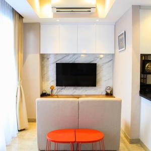 - un salon avec une télévision et un tabouret rouge dans l'établissement Stunning 3BR Apartment at The Branz BSD City By Travelio, à Samporo
