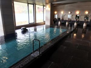 a swimming pool with a large tub and a large mirror at Hotel Nagaragawa No Sato in Gifu