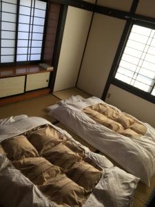 two unmade beds in a room with two windows at Shinshu Wakaho Gibier B&B in Nagano