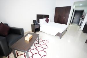 een slaapkamer met een bed, een tafel en een bank bij Aurak Guest House in Ras al Khaimah