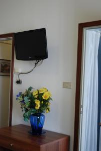 een vaas met bloemen op een tafel met een tv bij Hotel Tuscolano in Bologna