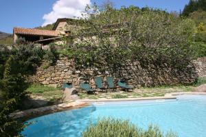 a pool with chairs next to a stone wall at Podere Pian De' Cortini in Serravalle