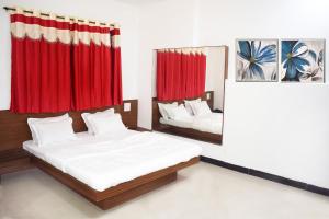 a bedroom with two beds and red curtains at Hotel Adarsh in Aurangabad +22 photos